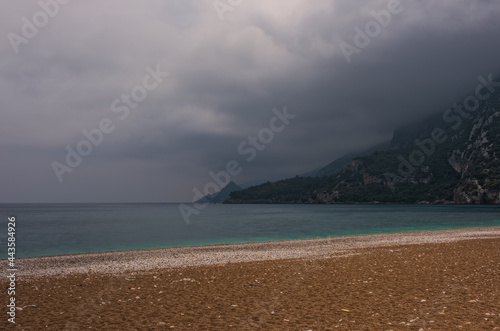 Fototapeta Naklejka Na Ścianę i Meble -  Morning on the beach in the village of Cirali. Blue bay in the Mediterranean at dawn. Landscapes of the Lycian Trail. May 2021. Long exposure picture