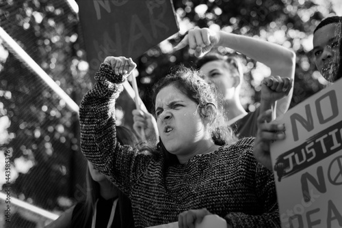 Closeup of angry teen girl protesting demonstration holding posters antiwar justice peace concept photo