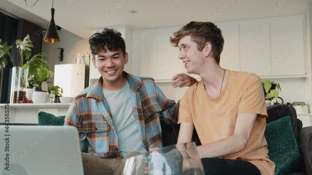 Young male caucasian couple engaging in video call with family waving to computer screen Young male caucasian couple engaging in video call with family waving to computer screen