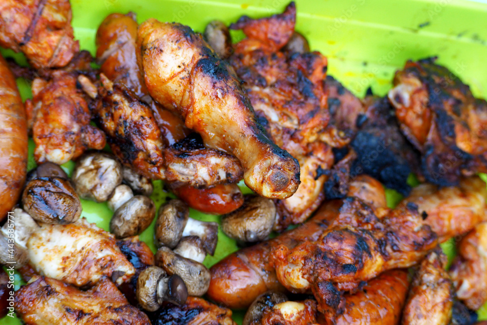 sausages, chicken wings and legs after grilling are on a green plate . barbecue