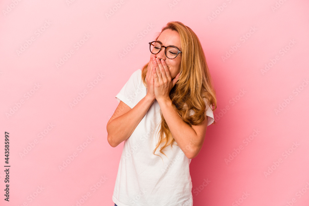 Caucasian blonde woman isolated on pink background laughing about something, covering mouth with hands. Caucasian blonde woman isolated on pink background laughing about something, covering mouth with hands.