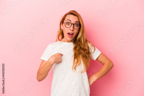 Caucasian blonde woman isolated on pink background surprised pointing with finger, smiling broadly.