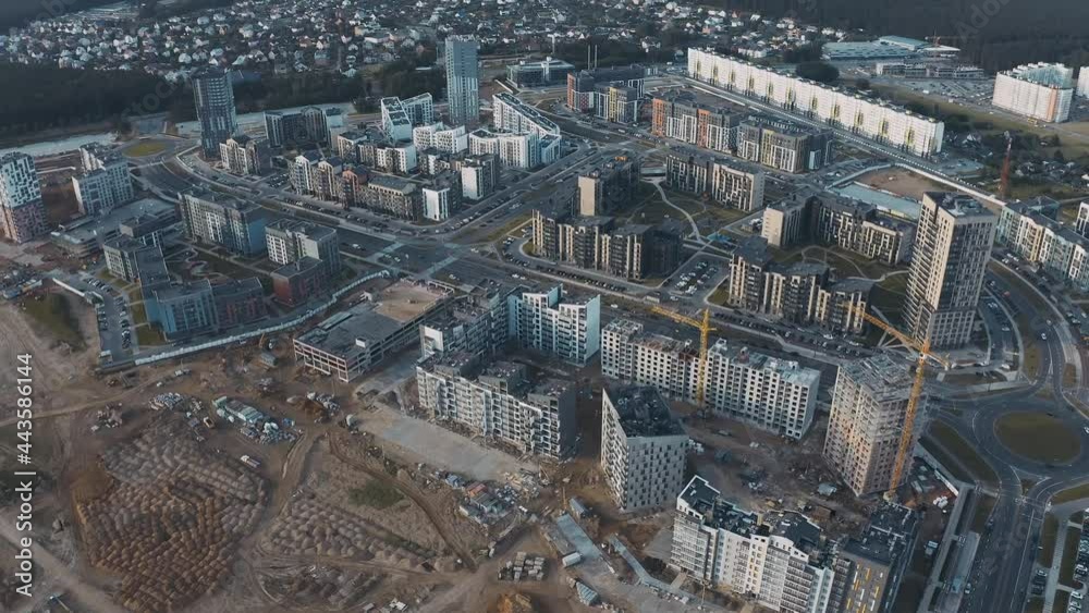 Process construction new quarter on city street aerial top view. Construction site with unfinished houses, building works, tower cranes and sand. Urban cityscape with roads and traffic cars