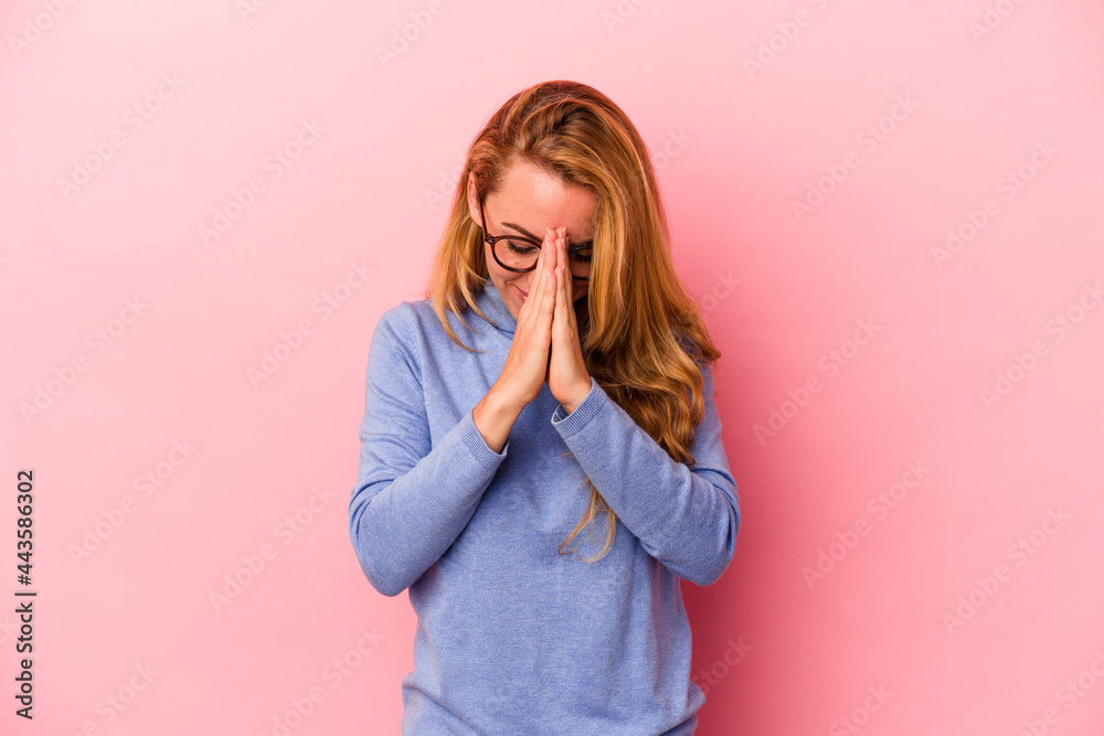 Caucasian blonde woman isolated on pink background praying, showing devotion, religious person looking for divine inspiration. Caucasian blonde woman isolated on pink background praying, showing devotion, religious person looking for divine inspiration.