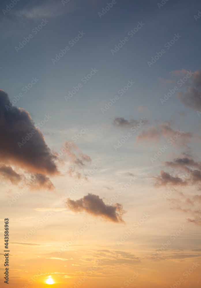 Colorful sunset or sunrise in the sky. The sky and clouds are painted in different bright orange, yellow and blue colors.