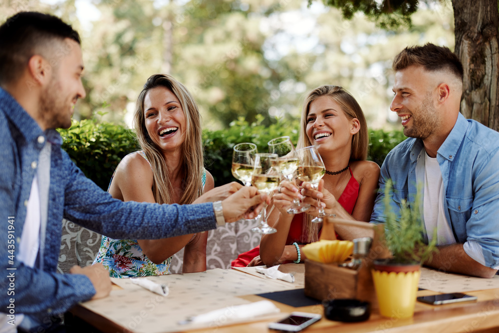 Group of Happy friends in the restaurant and toasting with glasses of wines Group of Happy friends in the restaurant and toasting with glasses of wines
