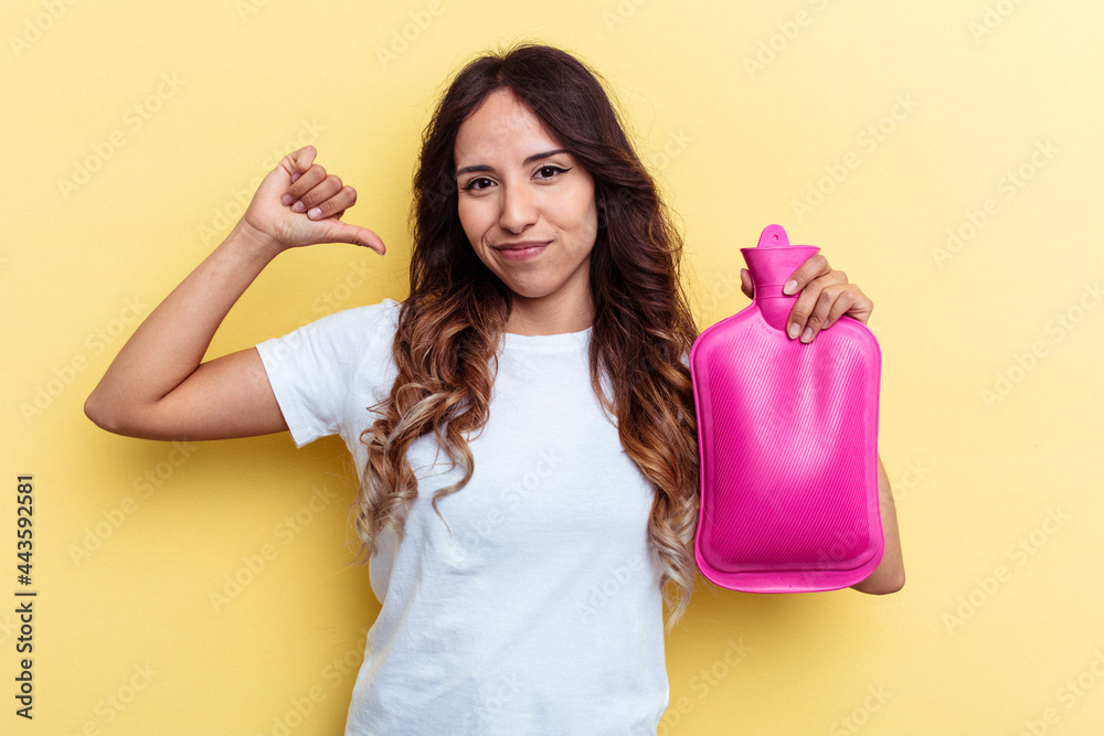 Young mixed race woman holding a hot bag isolated on yellow background feels proud and self confident, example to follow. Young mixed race woman holding a hot bag isolated on yellow background feels proud and self confident, example to follow.