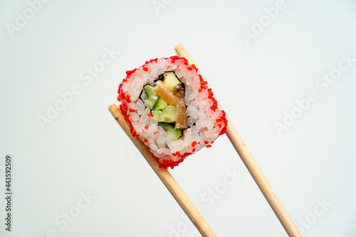 sushi sticks keep roll with caviar, fish, rice and avocado on white background
