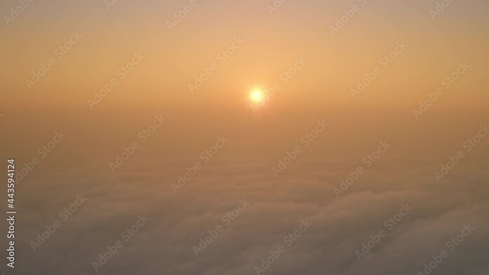 Morning sun rises on a thick swaying mist in a golden Haze, a morning celestial landscape with a Rising Sun. Shot of sunlight by a drone above the clouds. Morning sun rises on a thick swaying mist in a golden Haze, a morning celestial landscape with a Rising Sun. Shot of sunlight by a drone above the clouds.