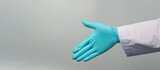 Hand shake wear doctor gown and blue medical glove on grey background. Studio shooting.