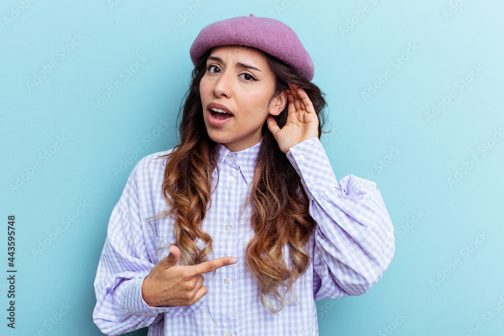 Young mexican woman isolated on blue background trying to listening a gossip. Young mexican woman isolated on blue background trying to listening a gossip.
