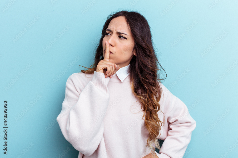 Young mexican woman isolated on blue background keeping a secret or asking for silence. Young mexican woman isolated on blue background keeping a secret or asking for silence.