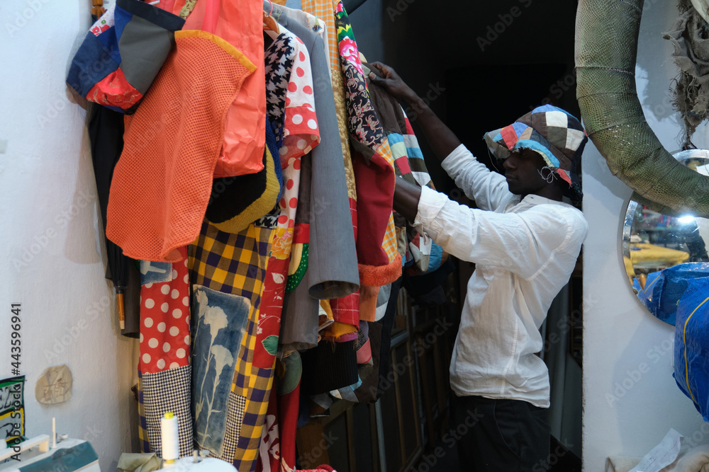 Black man choosing an african item of clothing to wear. African tailor in his sewing workshop.