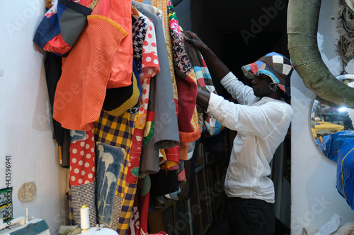 Black man choosing an african item of clothing to wear. African tailor in his sewing workshop.