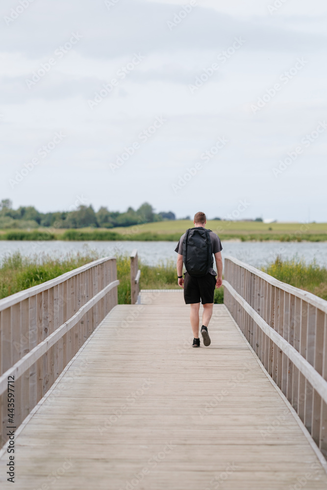 Hiker / trekker walking down bridge during summer Hiker / trekker walking down bridge during summer