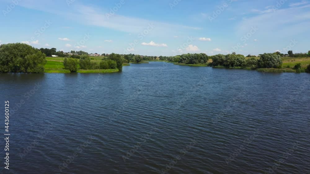 Aerial view of the river surrounded by green fields through which the river flows. Rural landscape in the countryside. Aerial view of the river surrounded by green fields through which the river flows. Rural landscape in the countryside.
