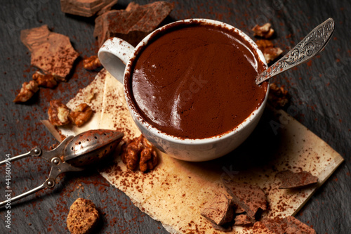 Cup of hot chocolate and pieces of chocolate on dark concrete background