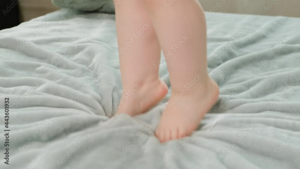 Close up of children feet jumping on blue blanket. Happy child jumping up and down on bed. Close up of children feet jumping on blue blanket. Happy child jumping up and down on bed.