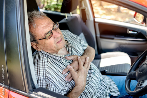 Mature man with chest pain suffering from heart attack in his car. Severe heartache, man suffering from chest pain, having heart attack or painful cramps, pressing on chest with painful expression.