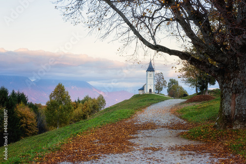 Scenic view of Jamnik church St Primus and Felician at sunset, Alps mountains, Slovenia. Beautiful landscape with footpath and sky with clouds, outdoor travel background, famous tourist attraction