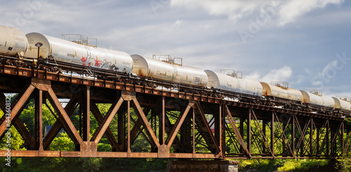 Long line of tanker cars traveling across railroad bridge. blue sky room for copy text.