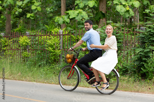 Couple cycling in park with fruts in basket on one bicycle, dating, family, love