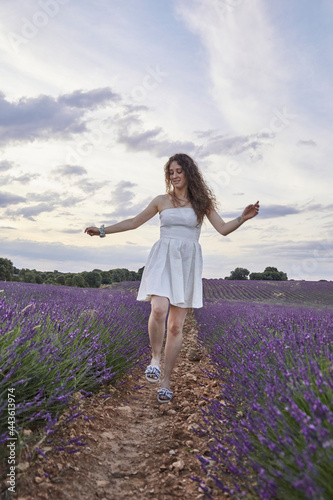 Fototapeta Naklejka Na Ścianę i Meble -  Woman in a white dress walks and has fun in the lavender fields