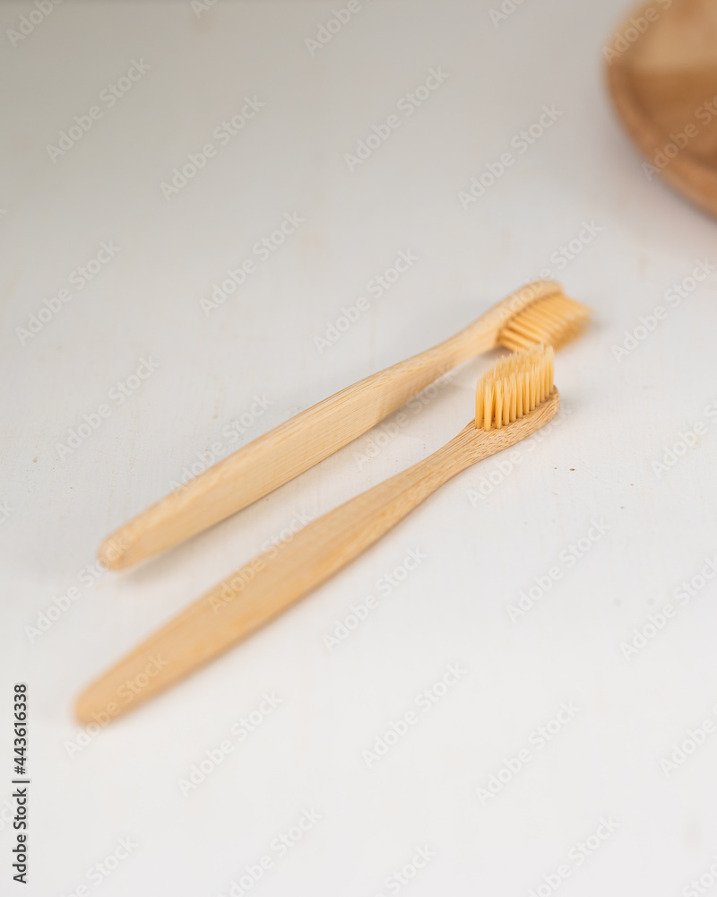 daily human hygiene, cotton swabs and cotton pads, a woman's hand holding bamboo toothbrushes on a light background in a glass or against the background of a wooden tray, eco-friendly personal hygiene daily human hygiene, cotton swabs and cotton pads, a woman's hand holding bamboo toothbrushes on a light background in a glass or against the background of a wooden tray, eco-friendly personal hygiene