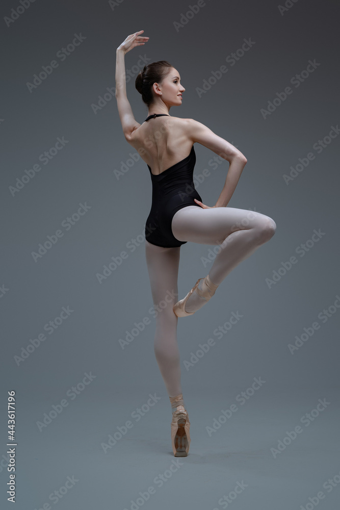 Elegant ballerina posing and dancing inside studio