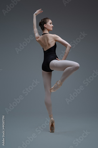 Elegant ballerina posing and dancing inside studio