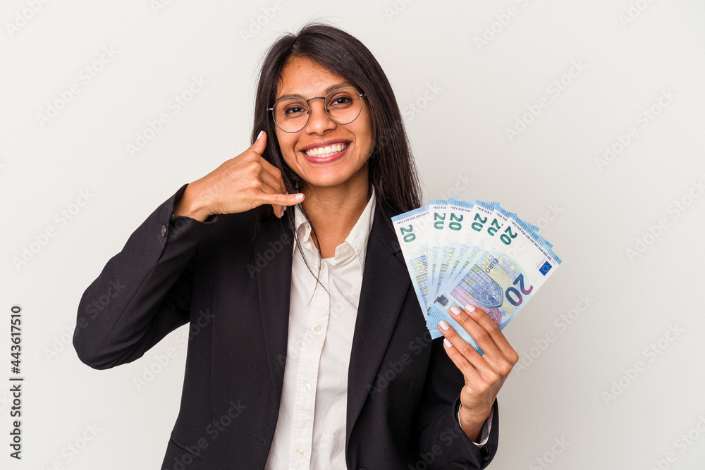 Young business latin woman holding bills isolated on white background showing a mobile phone call gesture with fingers. Young business latin woman holding bills isolated on white background showing a mobile phone call gesture with fingers.