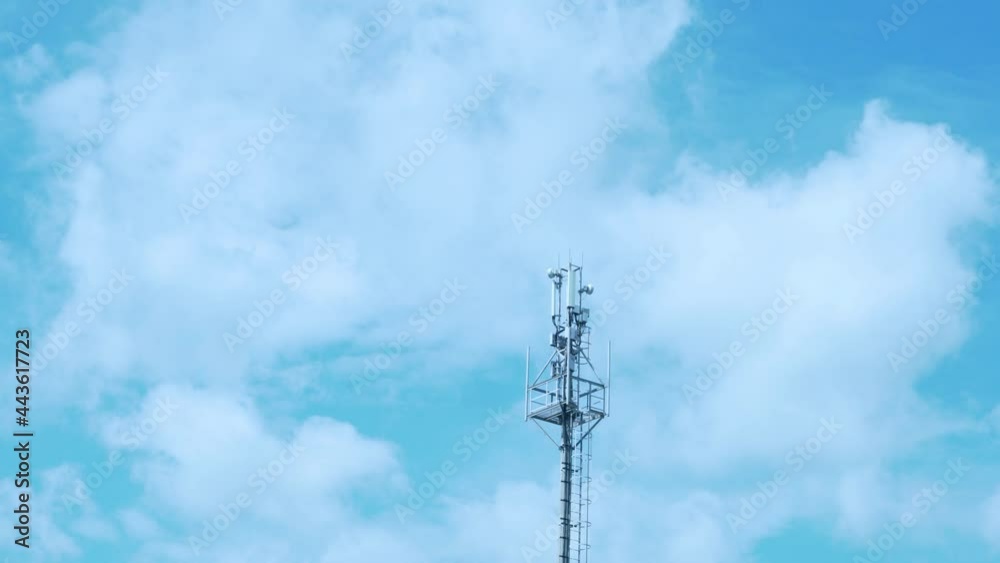 A Tower of GSM Mobile Operators, 3G, 5G Transmitter and A Beautiful Time Lapse of White Puffy Flying Clouds in A Blue Azure Sky. A Tower of GSM Mobile Operators, 3G, 5G Transmitter and A Beautiful Time Lapse of White Puffy Flying Clouds in A Blue Azure Sky.
