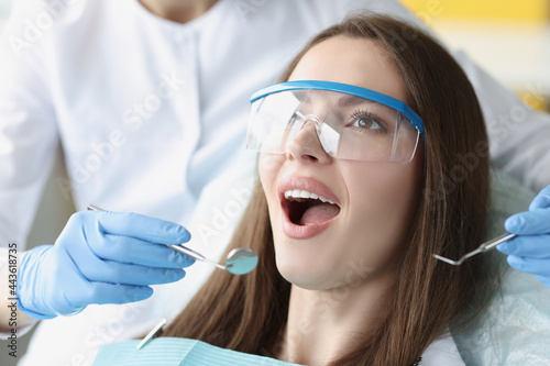 Smiling young woman undergoing treatment at dental clinic closeup