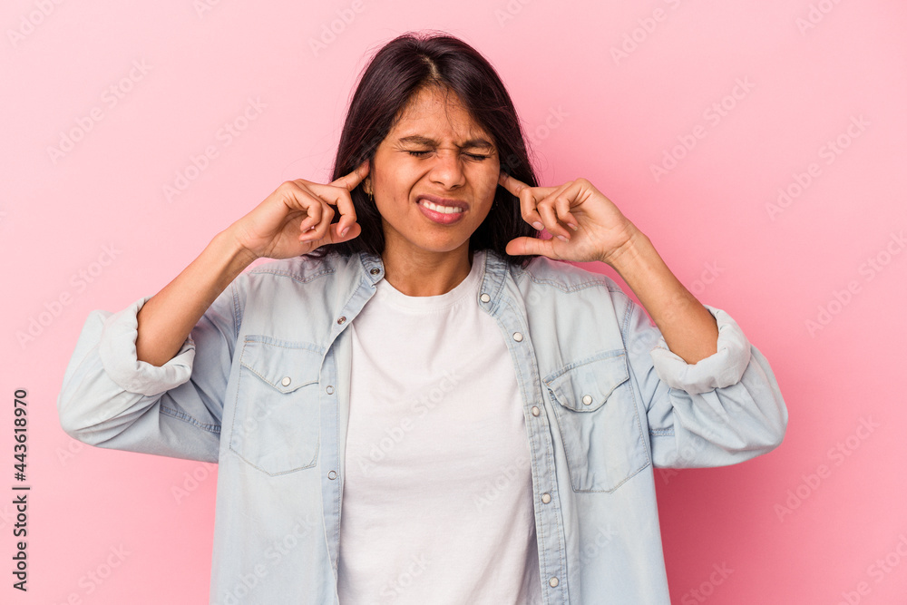 Young latin woman isolated on pink background covering ears with fingers, stressed and desperate by a loudly ambient. Young latin woman isolated on pink background covering ears with fingers, stressed and desperate by a loudly ambient.
