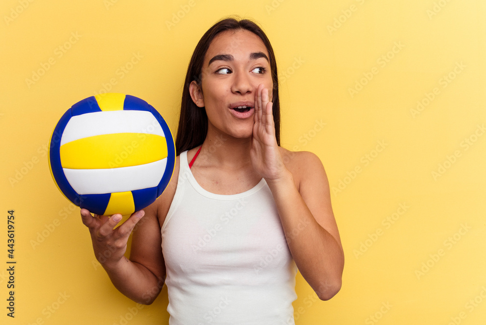 Young mixed race woman playing volleyball on the beach isolated on yellow background is saying a secret hot braking news and looking aside