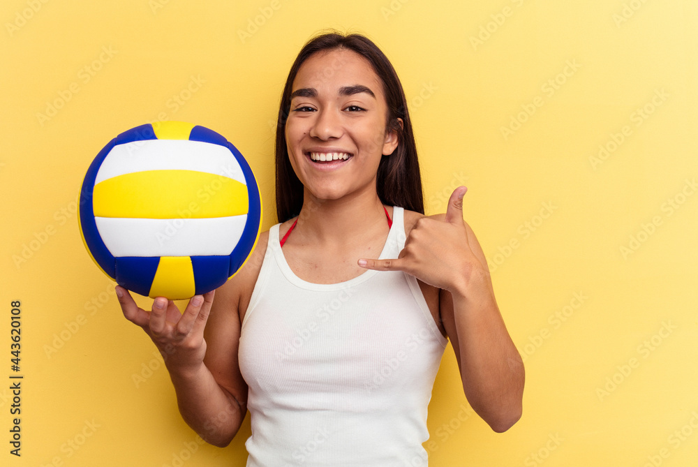 Young mixed race woman playing volleyball on the beach isolated on yellow background showing a mobile phone call gesture with fingers. Young mixed race woman playing volleyball on the beach isolated on yellow background showing a mobile phone call gesture with fingers.