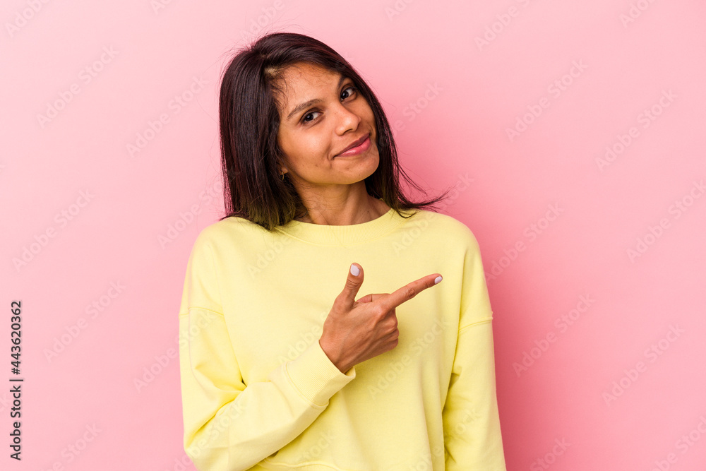 Young latin woman isolated on pink background smiling and pointing aside, showing something at blank space. Young latin woman isolated on pink background smiling and pointing aside, showing something at blank space.