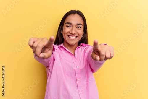 Young mixed race woman isolated on yellow background cheerful smiles pointing to front.