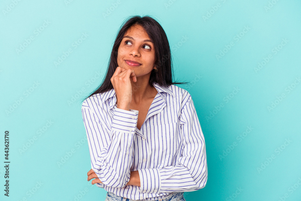 Young latin woman isolated on blue background relaxed thinking about something looking at a copy space. Young latin woman isolated on blue background relaxed thinking about something looking at a copy space.