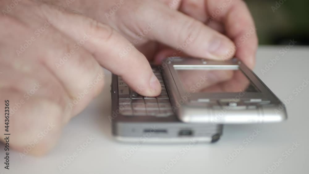 One Person Dialing a Phone Number Using an Old Mobile Phone with Detachable Keypad. Man Text Using an Old Technology Cellphone. One Person Dialing a Phone Number Using an Old Mobile Phone with Detachable Keypad. Man Text Using an Old Technology Cellphone.
