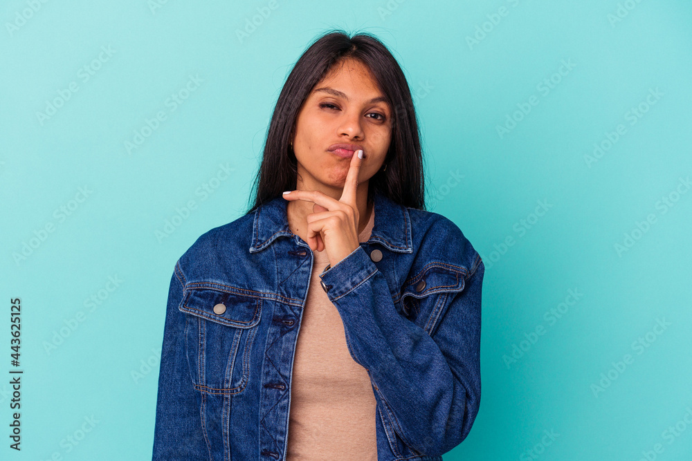 Young latin woman isolated on blue background thinking and looking up, being reflective, contemplating, having a fantasy. Young latin woman isolated on blue background thinking and looking up, being reflective, contemplating, having a fantasy.