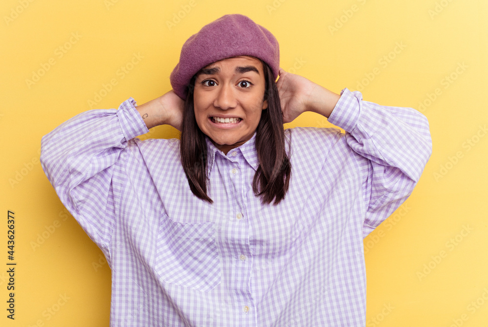 Young mixed race woman isolated on yellow background touching back of head, thinking and making a choice.