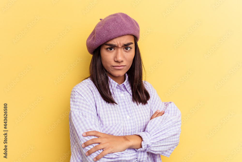 Young mixed race woman isolated on yellow background frowning face in displeasure, keeps arms folded. Young mixed race woman isolated on yellow background frowning face in displeasure, keeps arms folded.