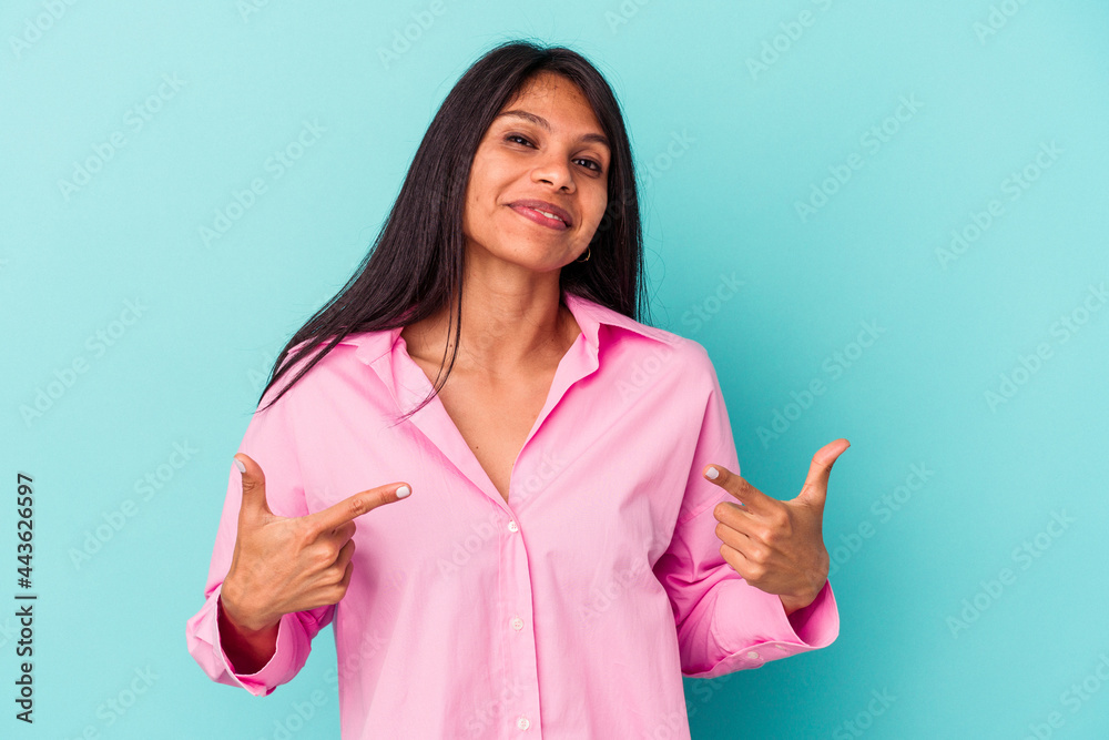 Young latin woman isolated on blue background person pointing by hand to a shirt copy space, proud and confident Young latin woman isolated on blue background person pointing by hand to a shirt copy space, proud and confident