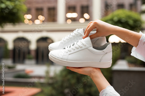 New white sneakers in a female hands at building background