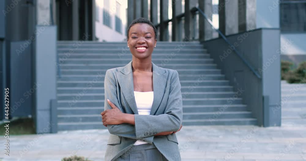 Waist up portrait view of smiling multiracial lady wearing white blouse and suit while standing near business centre and smiling. She is feeling confident Waist up portrait view of smiling multiracial lady wearing white blouse and suit while standing near business centre and smiling. She is feeling confident