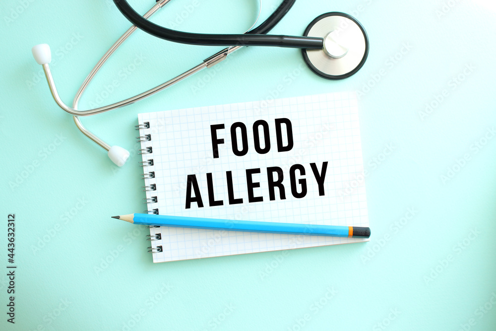 White notepad with the words FOOD ALLERGY and a stethoscope on a blue background. White notepad with the words FOOD ALLERGY and a stethoscope on a blue background.