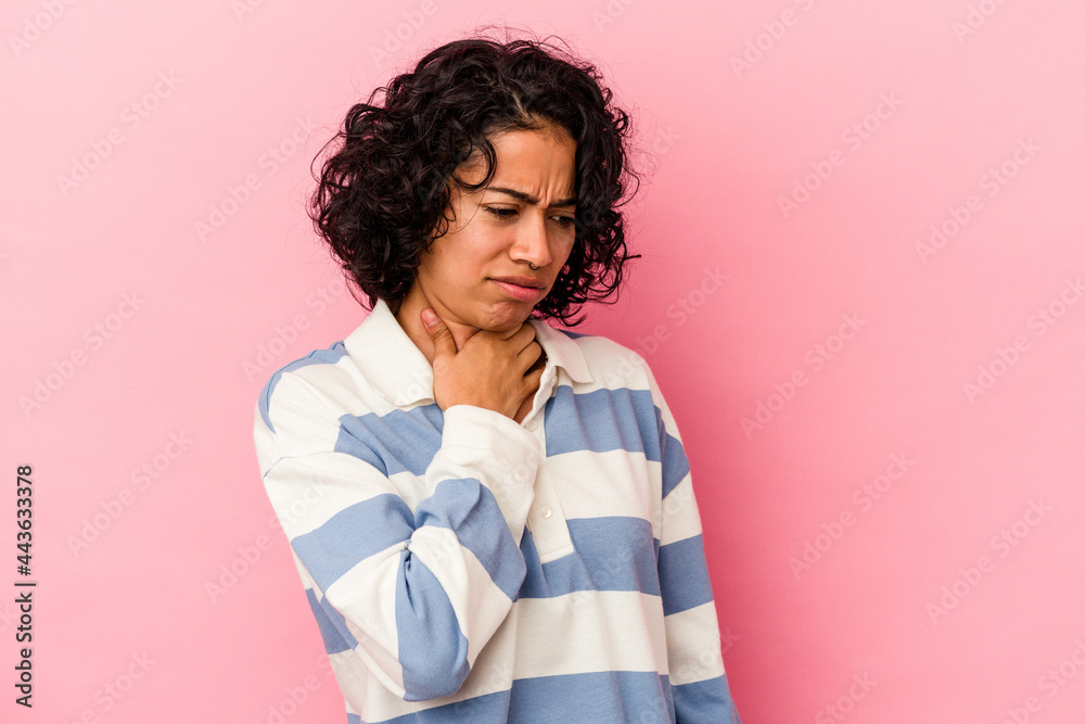 Young curly latin woman isolated on pink background suffers pain in throat due a virus or infection.