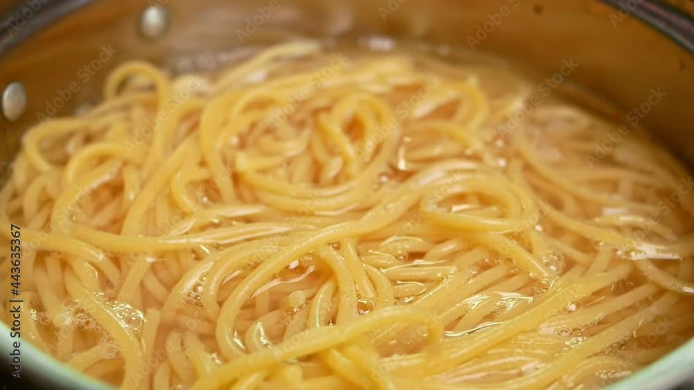 Raw spaghetti is being cooked in boiling water in a kitchen pot. Healthy Italian Food and Cooking concepts. Raw spaghetti is being cooked in boiling water in a kitchen pot. Healthy Italian Food and Cooking concepts.