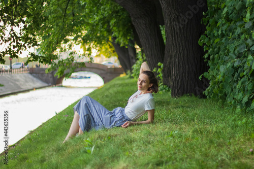 person sitting on the grass in the forest near river with bridge © Елена Дорнгоф